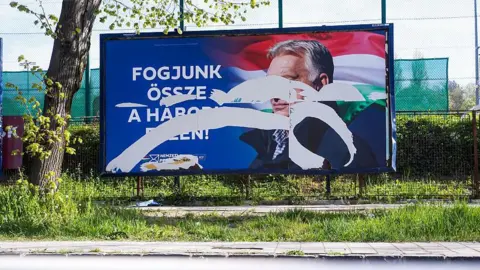 SOPA Images/LightRocket via Getty Images A torn political poster featuring Hungarian leader Victor Orban is seen near the polling station.