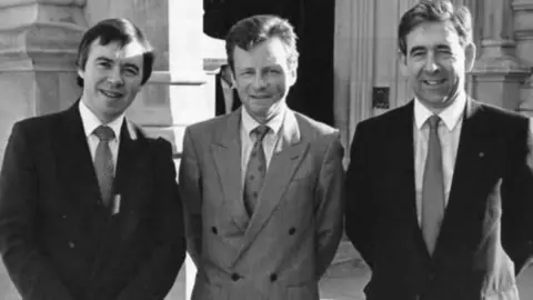 Plaid Cymru A black-and-white photo of the three men in dark suits, white shirts and ties with their hands behind their back