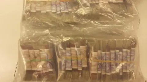 Avon and Somerset Police Stacks of pound notes in elastic bands in a transparent police evidence bag