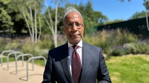 A man in a suit looks at the camera
