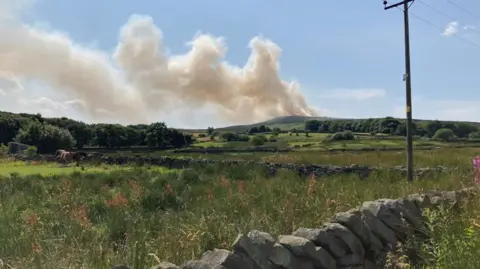 A picture taken miles away from the fire shows vast meadows in the West Yorkshire countryside with plumes of smoke rising in the background