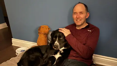 Photo supplied Michael Havet is seen today, stroking a black dog.