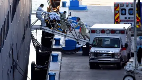 Getty Images A passenger being taken on a stretcher from the Zaandam cruise ship in Fort Lauderdale