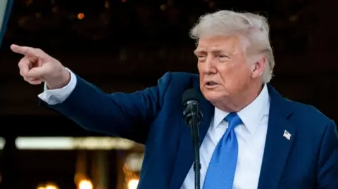 A close-up of President Donald Trump wearing a suit and addressing journalists 