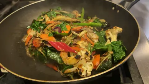 Chris McHugh / BBC A close up of a vegtable stir fry cooking in a frying pan. A variety of vegetables including rainbow chard, cauliflower and carrots can be seen