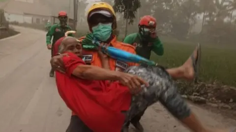 Reuters Elderly resident evacuated by a rescuer - picture supplied by BNPB