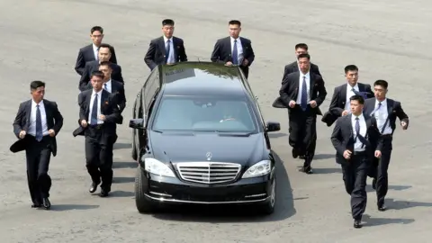 KOREA SUMMIT PRESS POOL Kim Jong-un's Mercedes car flanked by bodyguards at the Inter-Korean summit