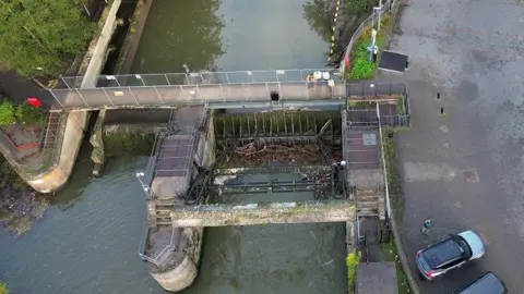 Environment Agency Aerial view of river gate and weir with lots of debris caught in gate