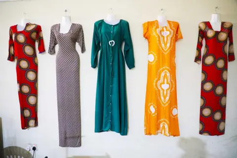 BBC Dresses sewn by former militants training as tailors hang on a wall