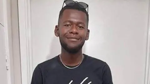 Tyreece Scott is seen smiling and has sunglasses on above his forehead. He is being pictured against a white background.