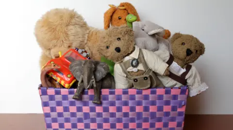 Getty Images A purple and pink box filled with children's toys, bears, rabbits, elephants, dinosaurs and cars. 