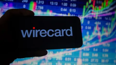 Getty Images Wirecard logo on phone against stock market charts.