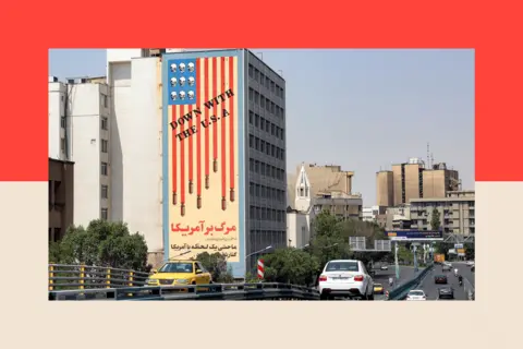 AFP via Getty Images Vehicles move along the Karim Khan Zand Bridge past the "Down with the USA" mural painted on the side of a building in central Tehran on June 13, 2025