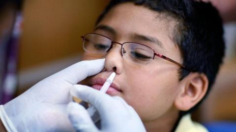 Boy receiving flu vaccine by nasal spray