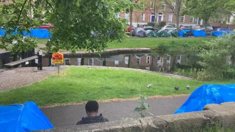 A young man resting beside a tent along the Grand Canal on Tuesday morning