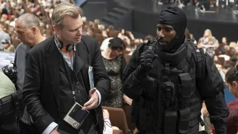 Warner Bros Tenet is directed by Christopher Nolan (left) and stars John David Washington