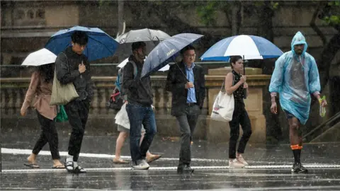 EPA Pedestrians hold umbrellas as they walk in heavy rain in Sydney's central business district on 17 January 2020.