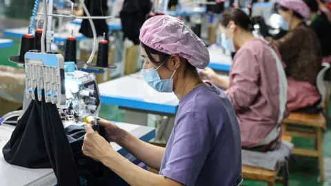 Getty Images A factory worker in China works at a sewing machine