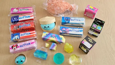 A selection of toys in plastic wrapping. Some of these squishy toys resemble foods such as chicken drumsticks, button bars, and bao buns. 