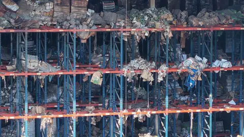 Getty Images The scaffolding of a warehouse is strewn with rotting packages of food