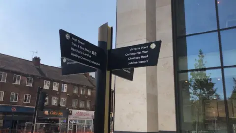 A sign directs people to different parts of Woking town centre, including Victoria Place, Commercial Way, Chertsey Road and Jubilee Square