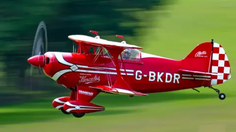 Clare Hartley A red propeller plane with white trip and a red and white checked tail