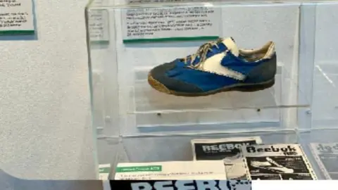 Hilary King An old blue running shoe sits on display behind a glass cabinet