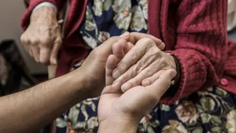 Getty Images Holding an older person's hand