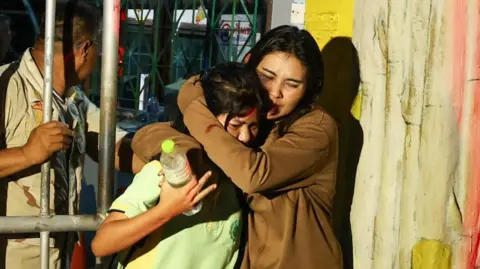 Two females hug as they leave the school where a siege happened 
