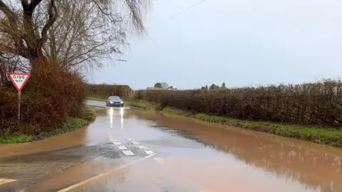 A car stops at a flooded road