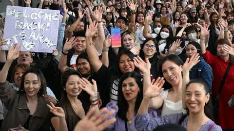 Getty Images This photo taken on June 13, 2025 shows fans of K-pop boy band BTS posing for photos as they queue up for the annual 'BTS Festa' celebrating the group's debut anniversary