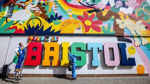 Plaster A large colourful mural on the side of a building, depicting Aardman animation characters. Below it is a large sign which reads 'made in Bristol', with each letter a different colour.