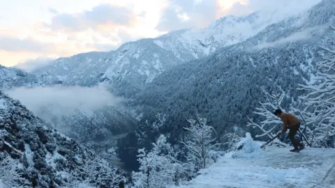 EPA A boy removes snow from his house in Neelum valley, Pakistani administered Kashmir, 14 January 2020