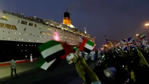 MARWAN NAAMANI Residents of Dubai wave the British and Emirati flags as the famous cruise liner arrives at its final destination