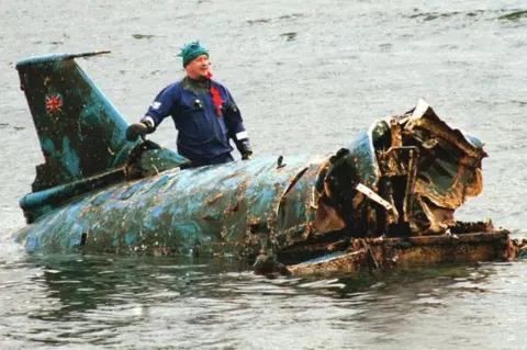 PA Bill Smith with the wreckage of Bluebird, which had been lifted from Coniston Water in 2001