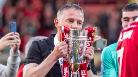 Wrexham boss Phil Parkinson kisses the trophy