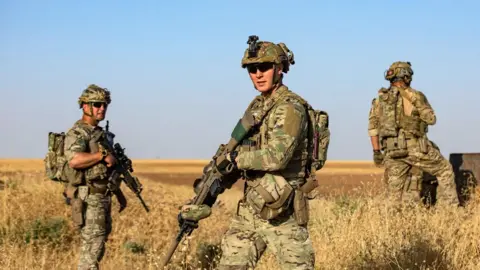 AFP A group of three US soldiers wearing camouflage and carrying rifles on patrol in a field