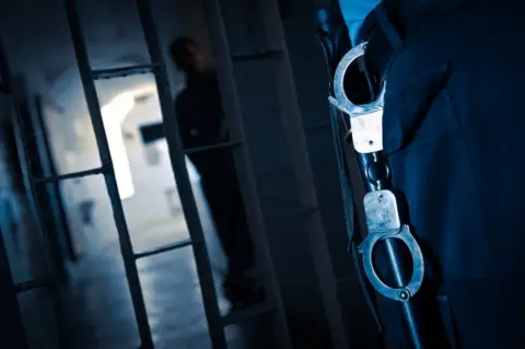 Getty Images Prison officer with prisoner in background