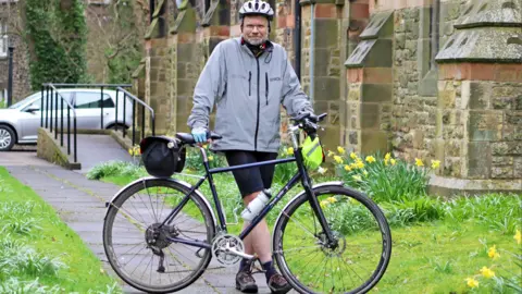 Bethany Browning/Newcastle diocese  Nigel Brown, the organist outside the church with his bike 