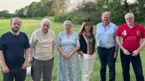 Six parish councillors standing in a green field. There are four women and two men. They are all wearing serious expressions.