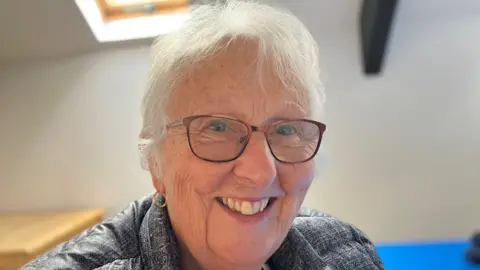 Lady wearing glasses and smiling at the camera 