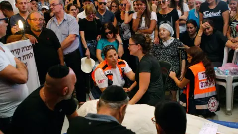 AFP Relatives and friends mourn beside the body of Yotam Ovadia at a Jerusalem cemetery on 27 July 2018