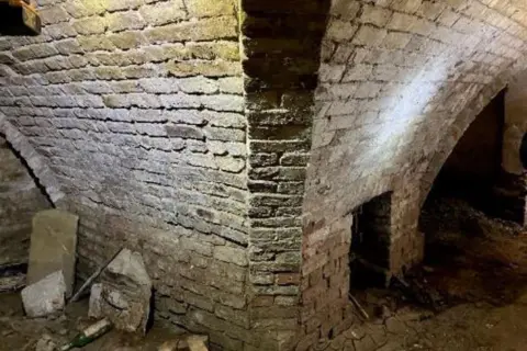 Yew Tree Hall The basement has a fireplace made out of kiln. Rubble is strewn all over the floor.