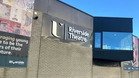 The Riverside Theatre building on the Coleraine campus. A number of banners are seen on the outside of the building. 