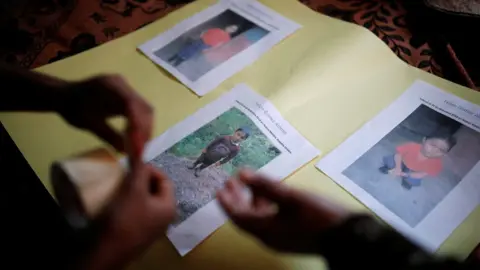 Reuters The family of Felipe Alonzo-Gomez arranges photos of the dead boy in the village of Yalambojoch, Guatemala, 27 December