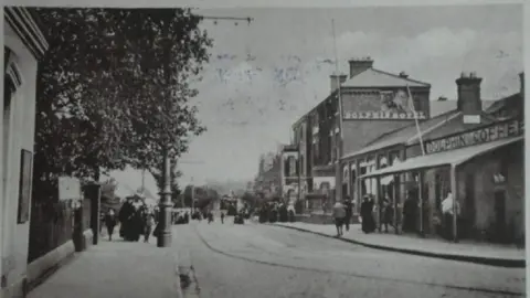 A black and white photograph of the Dolphin Hotel in the 1800s, with people on the pavements wearing Victorian attire.