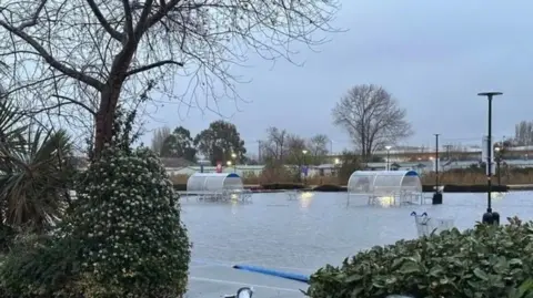 A flooded car park of Tesco in Bognor Regis. The trolley bays are visible but partially filled with water.
