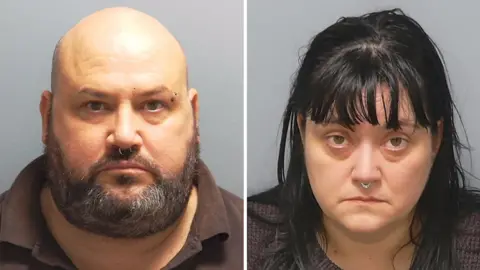 Custody photos of Richard Elkin and Hayley Bell. He is bald with a greying beard and a ring through his nose. She has black hair over her shoulders, a fringe and also has a ring through her nose.