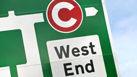 Getty Images A close up of a green traffic sign with the congestion charge logo in red and directions to the West End of London. 