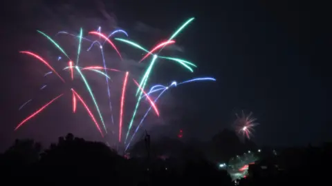 PA Media Fireworks in red, blue and green streaks across night sky 